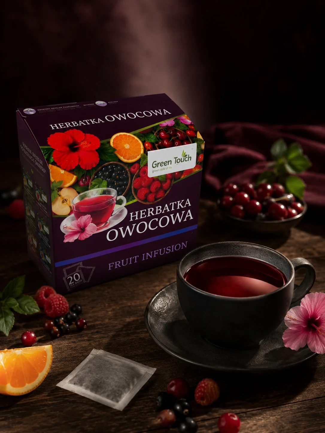 Green Touch Owocowa obok filiżanki czerwonego naparu, filtrów, owoców i kwiatu.