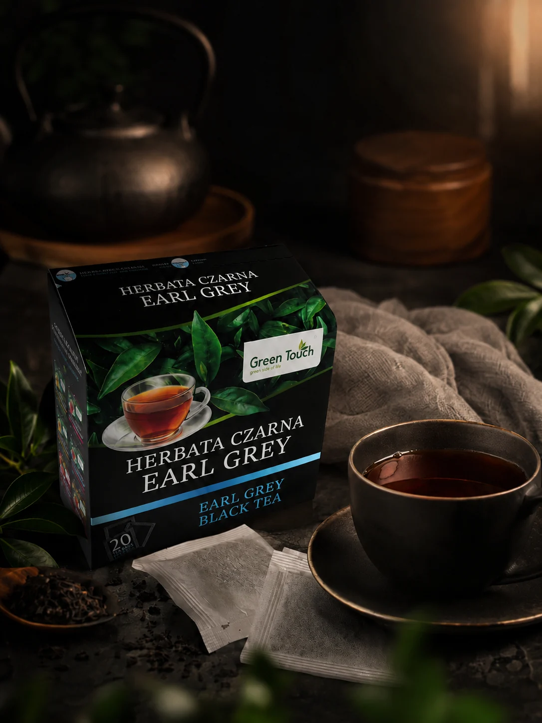 Green Touch Earl Grey obok filiżanki i filtrów, z czajnikiem w tle.